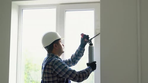 Construction Worker Applying Spray Foam to Window