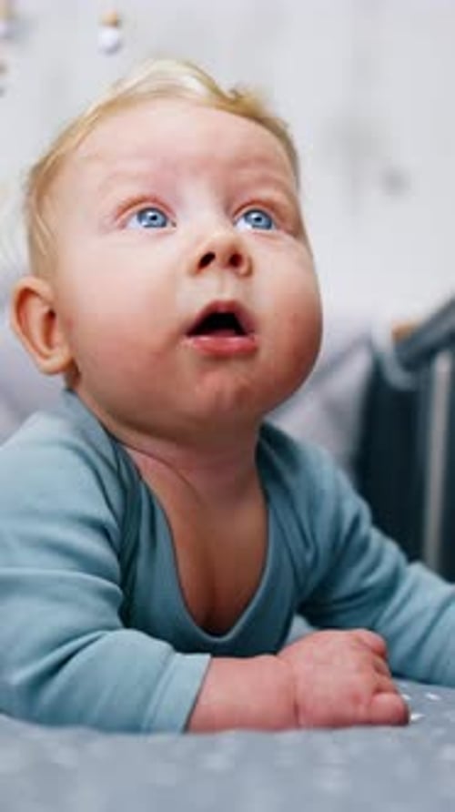 Adorable blond kid lies peacefully in the cot. Lovely baby portrait lying on belly in the crib.