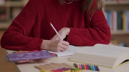 Close view of unrecognizable girl writing and reading at library