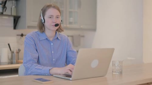 Thumbs Up by Young Woman with Headset in Call Center