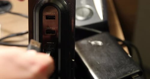 Plugging in a usb cable into a dusty usb hub on a cluttered desk