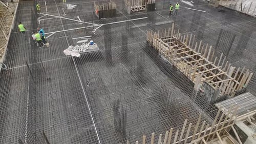 Luftaufnahme bei der Installation eines Abwassersystems auf einer großen Baustelle: Arbeiter, die Rohre verlegen
