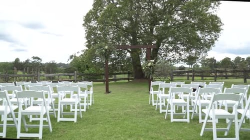 Outdoor Wedding Venue with White Chairs and Arch