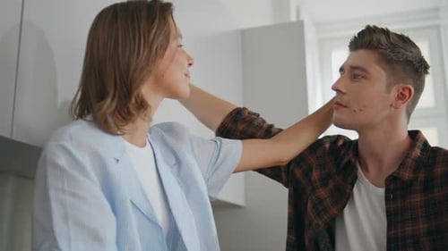 Affectionate Couple: Man Kisses Woman's Hand in Kitchen