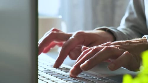 Male Hands Typing Keyboard on Laptop Computer Man Working Online at Home Searching Information