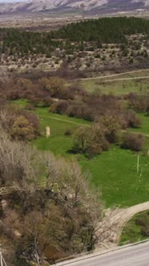 Vue aérienne d'une large route qui serpente à travers les champs verts couverts d'arbres, prise de vue sur une belle vallée