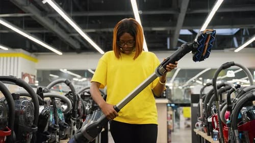 Woman Inspecting Vacuum Cleaner in Appliance Store