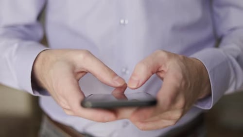 Holds the Phone in His Hands Typing in the Smartphone Application Conducts Business Through the