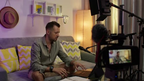 Man recording a podcast or vlog in a cozy home studio with video equipment