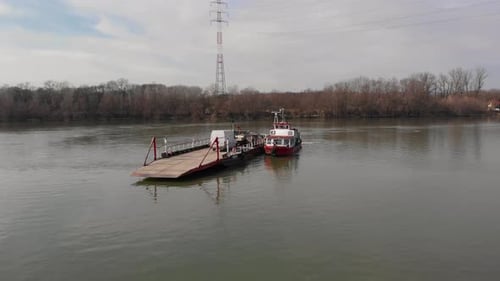 Orbital aerial shot around a ferry boat on a river, loaded with cars and people