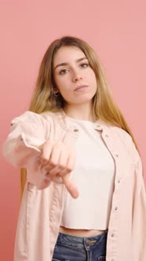 Young Adult Giving Thumbs Down on Pink Background