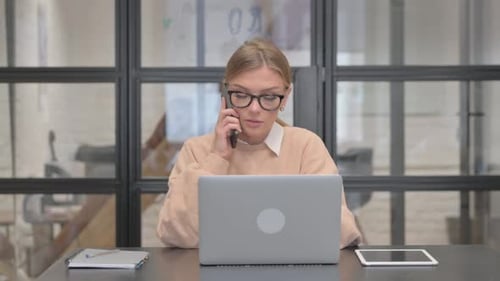 Woman Talking on Phone While Working on Laptop