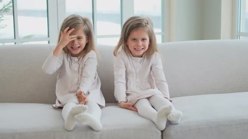 Two Young Girls Laughing Together on Couch