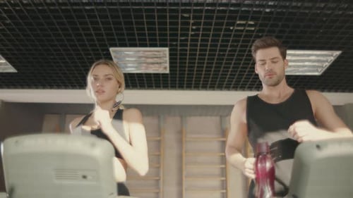 Handsome Man Flirting with Woman on Treadmill Machine in Fitness Club. Runner