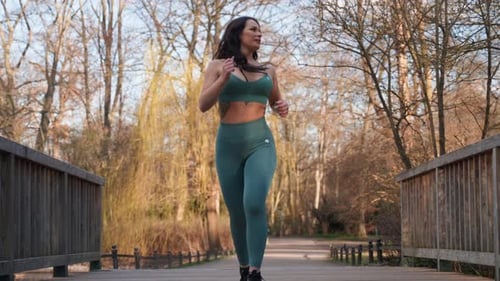 Young strong sexy muscular fit woman in sportswear jogging in the park.