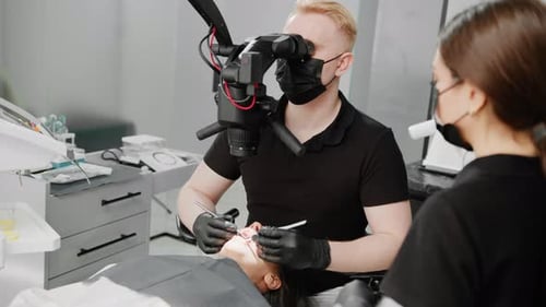 At the dental clinic a dentist examines a patient with a toothache under a microscope