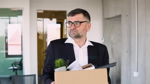 Trauriger entlassener älterer Angestellter nimmt seine Büroartikel aus dem Büro mit