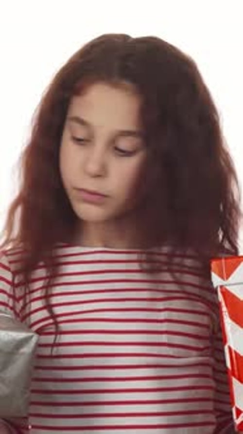 Thoughtful Girl Playfully Choosing Between Two Vibrant Gifts