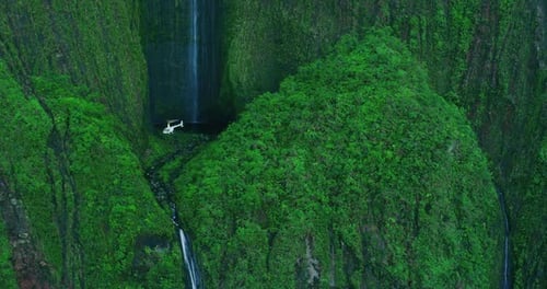 Hélicoptère planant au pied d'une immense cascade