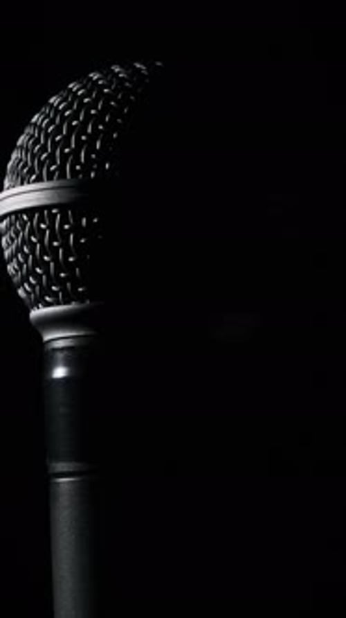 Dynamic Microphone Slowly Rotates in Backlight on Black Background