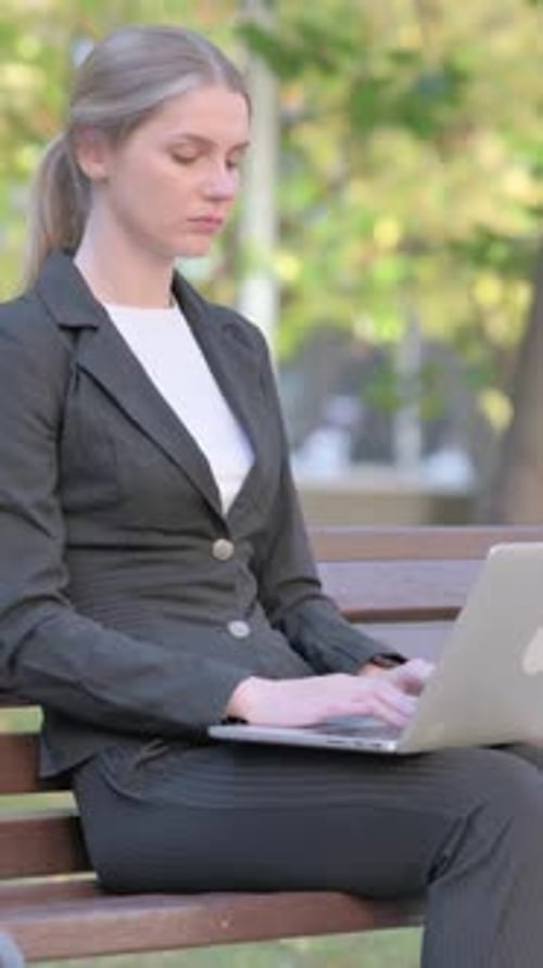 Woman in Suit Working on Laptop in Park