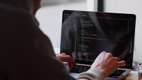 Rear View of a Man Writing Code on His Laptop Closeup of a Male Web Programmer Working Remotely