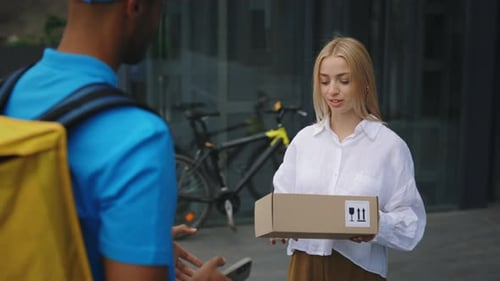 African American Male Courier in Special Uniform Carrying the Backpack Delivers Package to a