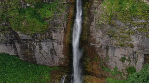 Majestic waterfall cascading down rocky cliffs surrounded by lush greenery