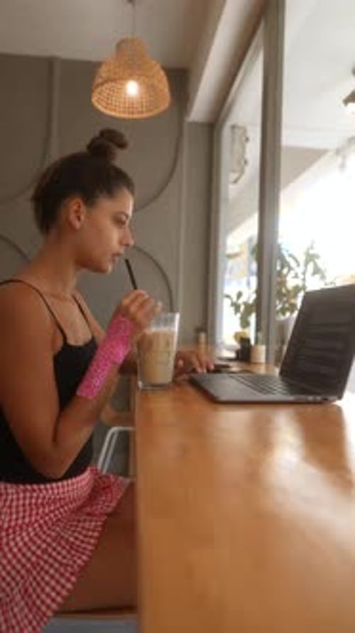 Woman Enjoying Coffee While Working on Laptop in Caf