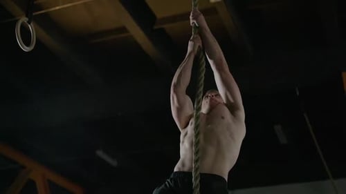 Athletic Man in Gym Man Climbing on a Rope Muscle Training with Weights Crossfit