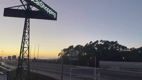 Vibrant Orange Sky at Sunset Over a Busy Highway, with a Large Billboard Reading ‘Shopping’ Casting