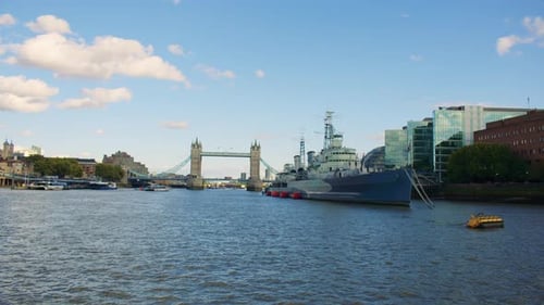 Tower Bridge, royal warship and the River Thames panorama under a bright blue sky.