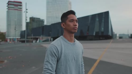 Man Walks in Urban Area with Modern Buildings