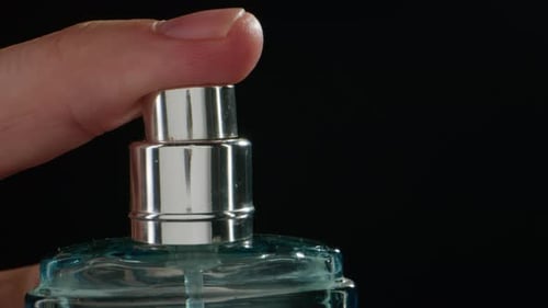 Junger Mann, der im Dunkeln Parfüm auf die Haut aufträgt, Nahaufnahme des Sprühens eines Deodorants, Luxus-Parfüm