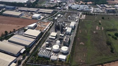 High aerial view showing a large industrial plant complex with storage tanks, pipelines, and