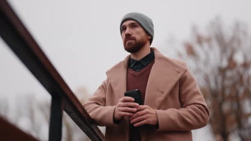 Stylish Man with Beard Stands Outdoors in Autumn