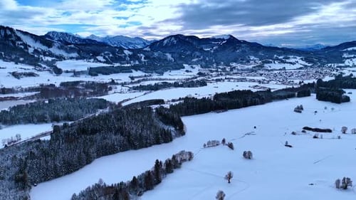 Scenic view of a snow-covered valley with trees and mountains in the background.