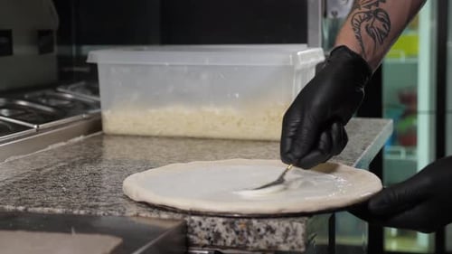 The Chef Applying White Sauce to the Pizza Dough in the Restaurant Kitchen