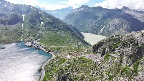 Drone pushes towards, stunning blue lake surrounded by green stone mountains, road passes through un