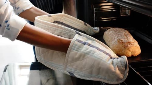 Biracial woman wearing apron and baking bread in kitchen, slow motion
