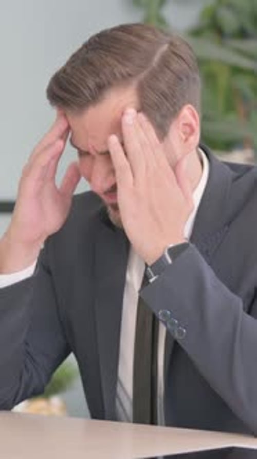 Businessman Massaging Temples Suffering from Headache at Work