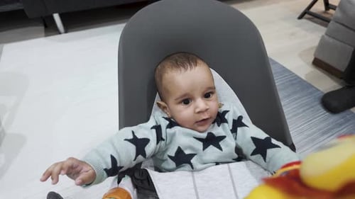 Cute Infant Playing with Toy in High Chair