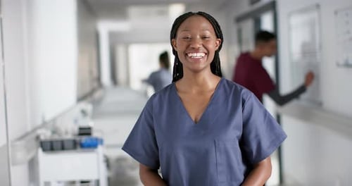 Portrait of happy african american female doctor wearing scrubs in hospital, slow motion