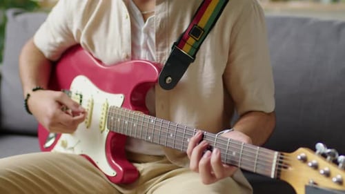 Young Adult Playing Electric Guitar on Couch