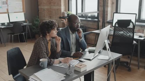 Two Office Managers Looking at Screen Having Project Discussion