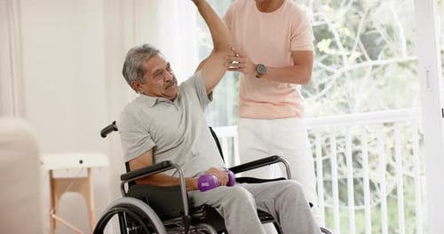 Senior Man Lifting Weights With Young Adult Assistant