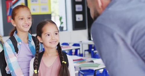 Diverse male teacher and happy schoolchildren in school classroom