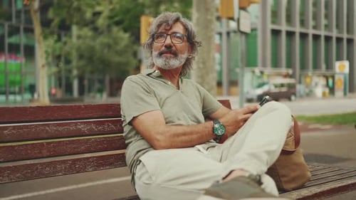 Man Sitting On Park Bench Using Mobile Phone