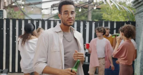 Portrait of Joyful Biracial Guy Relaxing Dancing Holding Bottle Chilling at Open Air Party in Bar