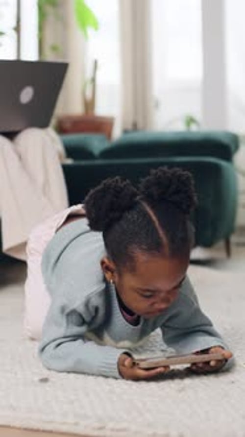 Girl Plays on Smartphone While Adult Works Nearby